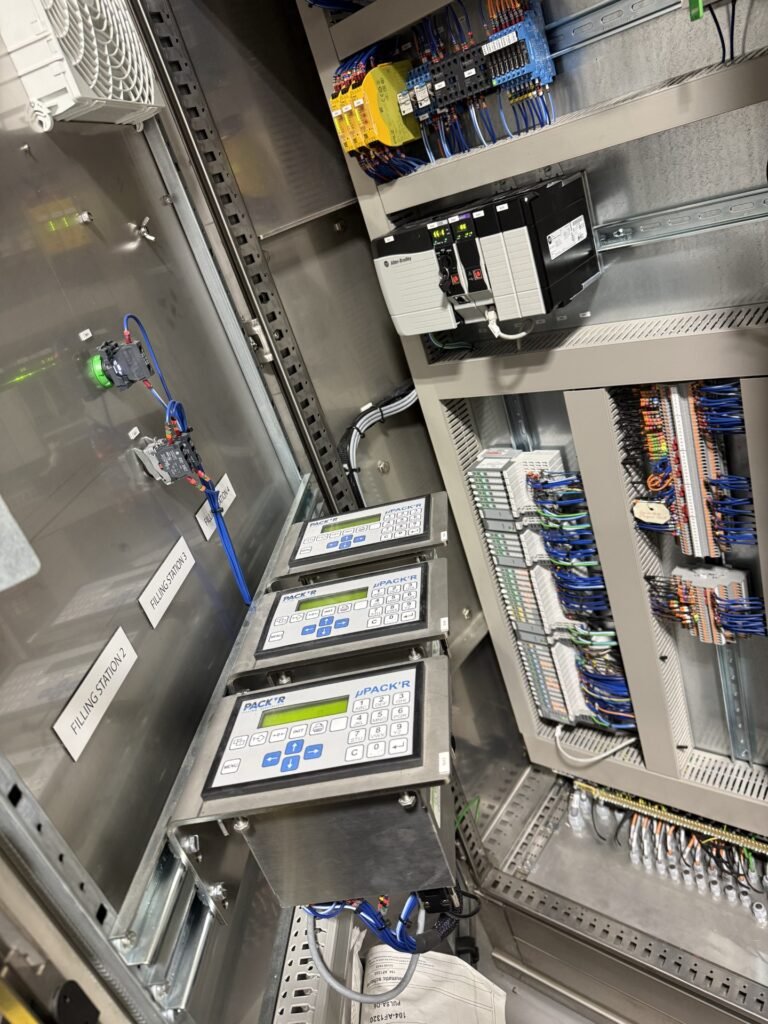 Close-up of an open industrial control panel used for drum filling with multiple circuit boards and color-coded wiring.